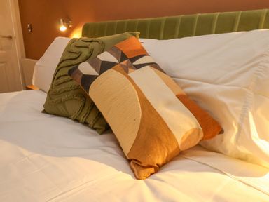 A bed with white sheets and two decorative pillows and a green headboard at Picadore Two in Scarborough
