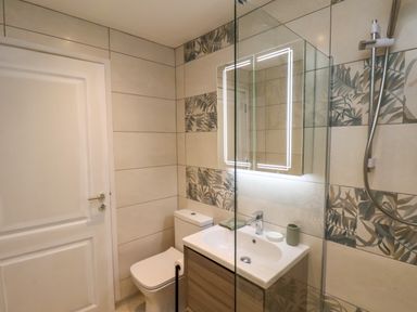 A bathroom with a toilet sink with vanity and a mirror with lights at Picadore Two in Scarborough