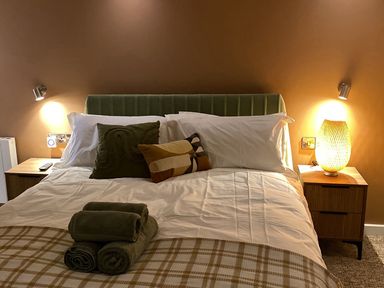 A bedroom with a bed with pillows and folded towels on it and bedside tables with lamps at Picadore Two in Scarborough