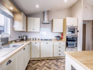 A kitchen with cabinets, sink, cooker, and oven at Lodge 58 at Riviera Bay Coastal Retreat Brixham