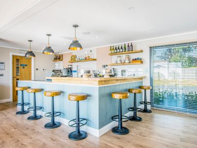 A bar with stools and shelves at Lodge 58 at Riviera Bay Coastal Retreat Brixham