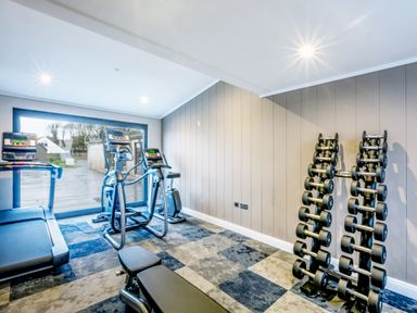 A gym with fitness equipment including a treadmill and dumbbells at Lodge 62 at Riviera Bay Coastal Retreat in Brixham