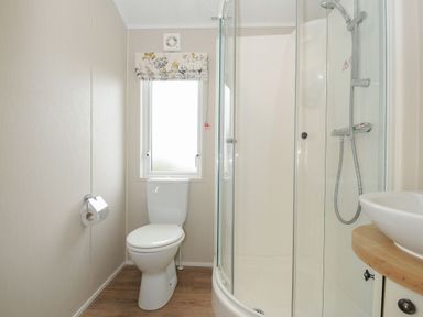 A bathroom with a toilet shower sink and a window at Lodge 69 at Riviera Bay Coastal Retreat in Brixham