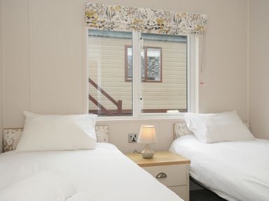 A bedroom with two single beds and a nightstand with a lamp at Lodge 69 at Riviera Bay Coastal Retreat in Brixham
