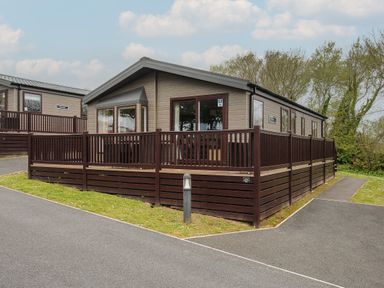 A small cabin with a wooden fence around a patio in a park setting at Lodge 68 at Riviera Bay Coastal Retreat in Brixham