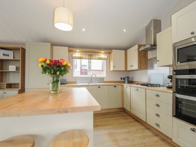 A kitchen with wooden countertops a flower vase on a counter and built in oven and stove at Lodge 70 at Riviera Bay Coastal Retreat in Brixham