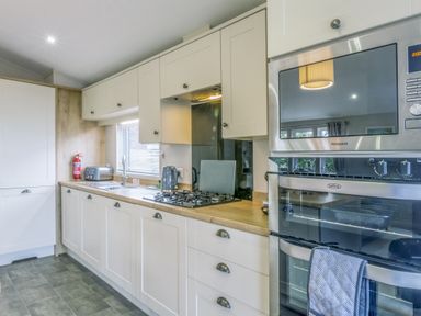 A kitchen with a gas stove and oven at Lodge 71 at Riviera Bay Coastal Retreat Brixham