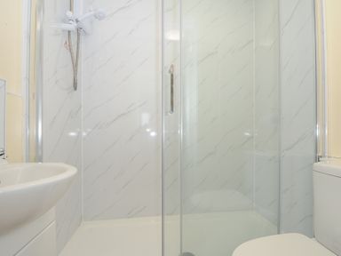A bathroom with a shower enclosure a sink and a toilet at Chalet 7 at Landscove Holiday Park in Brixham