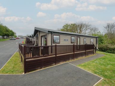 A row of single story cabins with wooden fences and patios along a paved road at Lodge 72 at Riviera Bay Coastal Retreat in Brixham