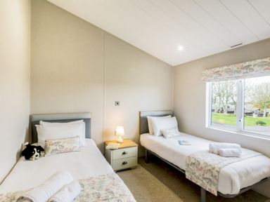 A bedroom with two beds and a nightstand at Lodge 72 at Riviera Bay Coastal Retreat in Brixham