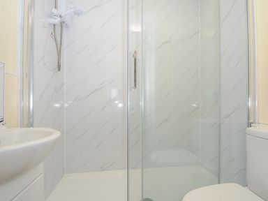 A bathroom with a shower enclosure a sink and a toilet at Chalet 15 at Landscove Holiday Park in Brixham