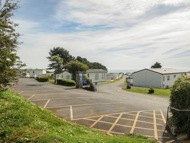 A holiday park with parked caravans and trees under a partly cloudy sky at Chalet 15 at Landscove Holiday Park in Brixham