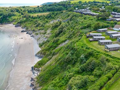 A beach with cliffside holiday homes at Chalet 15 at Landscove Holiday Park in Brixham