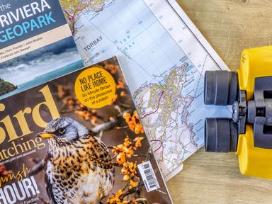 A map and binoculars with a birdwatching magazine at Chalet 34 at Landscove Holiday Park Brixham
