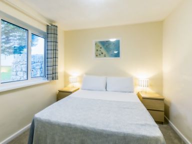 A bedroom with a bed and nightstand at Chalet 34 at Landscove Holiday Park Brixham