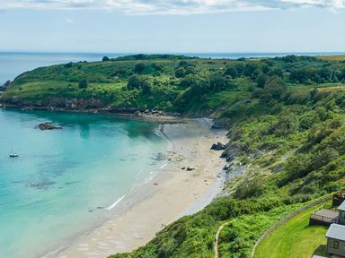 A beach with water and hills at Chalet 34 at Landscove Holiday Park in Brixham