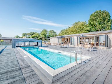 An outdoor area with a swimming pool and seating at Chalet 34 at Landscove Holiday Park Brixham