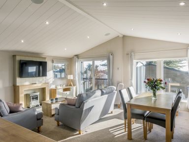 A living room with a sofa and dining table at Lodge 15 at Landscove Holiday Park Brixham