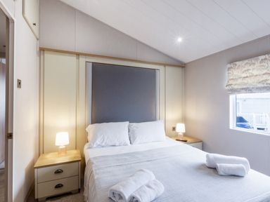 A bedroom with a bed and bedside tables at Lodge 15 at Landscove Holiday Park Brixham