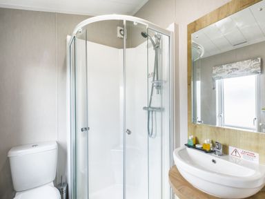 A bathroom with a shower and sink at Lodge 15 at Landscove Holiday Park Brixham