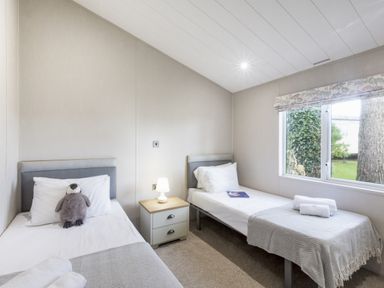 A bedroom with two beds and a window at Lodge 15 at Landscove Holiday Park Brixham