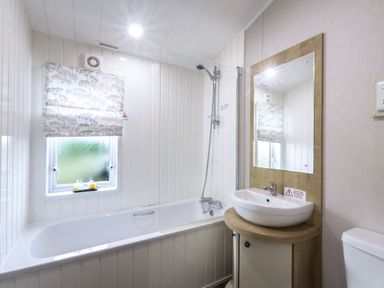 A bathroom with a bathtub and sink at Lodge 15 at Landscove Holiday Park Brixham