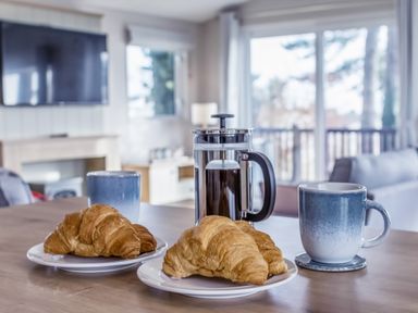 A dining table with croissants and coffee at Lodge 9 at Landscove Holiday Park Brixham
