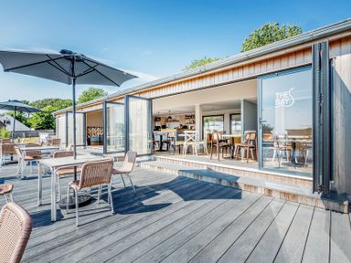 An outdoor dining area with tables and umbrellas at Lodge 9 at Landscove Holiday Park Brixham