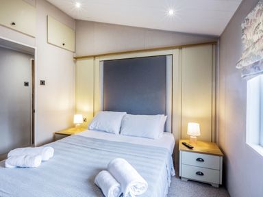 A bedroom with a bed and bedside table at Lodge 11 at Landscove Holiday Park Brixham