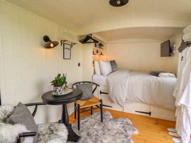 A small bedroom with a bed table chairs and a TV at La'al Ling in Penrith