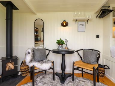 A seating area with two chairs and a small round table next to a wood stove at La'al Ling in Penrith