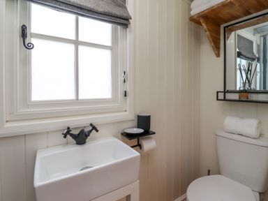 A bathroom with a white sink black faucet window mirror shelf and toilet at La'al Ling in Penrith