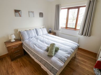 A bedroom with a double bed striped bedding two bedside tables with lamps and a window with curtains at Rossaveel Upper in Rossaveel County Galway