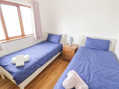 A bedroom with two single beds with blue bedding and a wooden nightstand with a lamp between them at Rossaveel Upper in Rossaveel County Galway