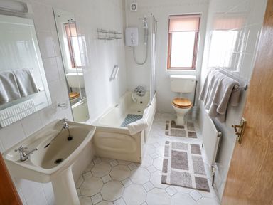 A bathroom with a sink a bathtub with shower a toilet and towels on a rack at Rossaveel Upper in Rossaveel County Galway