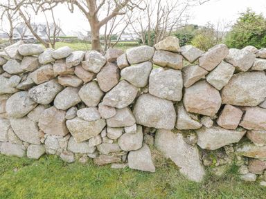 A stone wall with irregularly shaped rocks and grass at the base at Rossaveel Upper in Rossaveel County Galway