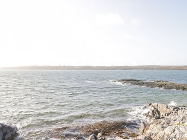 A rocky shoreline with waves and an island in the distance at Rossaveel Upper in Rossaveel County Galway