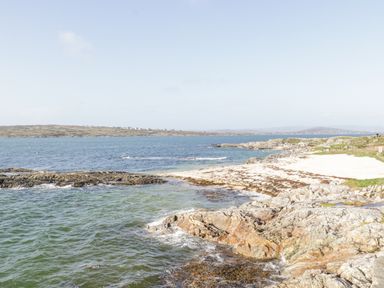 A rocky coastline with a small sandy beach and calm sea at Rossaveel Upper in Rossaveel County Galway