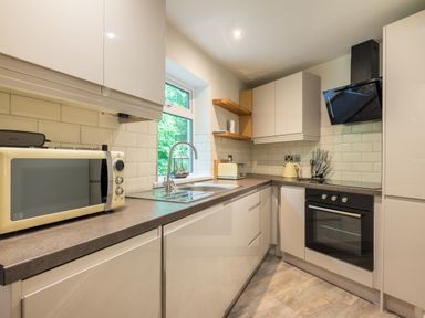 A kitchen with a microwave toaster kettle sink oven and cabinets at Ullswater View Apartment in Ullswater