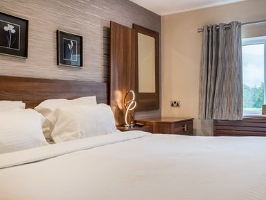 A bedroom with a bed pillows bedside table lamp mirror window with curtains and framed pictures on the wall at Ullswater View Apartment Ullswater