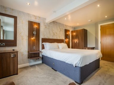 A bedroom with a double bed bedside shelves wardrobe and a dresser with a mirror at Ullswater View Apartment in Ullswater