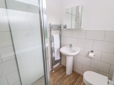 A bathroom with a shower, pedestal sink, toilet, mirror cabinet, towel rack with towels, and tiled walls at Bod A Quinte in Carbis Bay