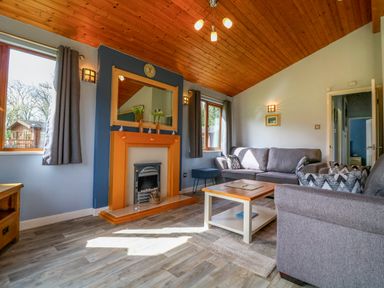 A living room with two gray sofas a wooden coffee table a fireplace and wooden ceiling at 3 The Glade in St Minver Rock