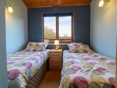 A bedroom with two single beds and a bedside table with a lamp in between at 3 The Glade in St Minver Rock
