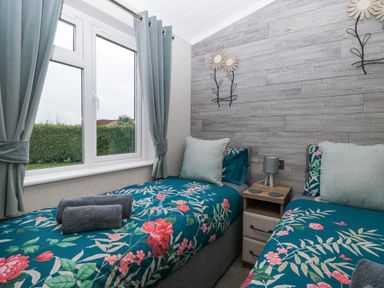 A bedroom with two single beds with floral bedding and a window with curtains at Wurzburc in Swaffham