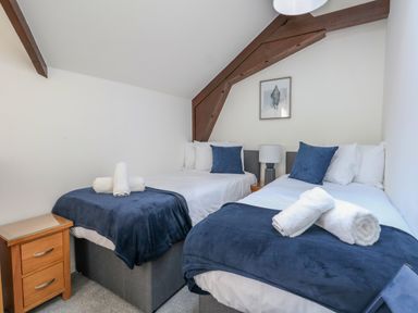 A bedroom with two single beds nightstand lamp and a framed picture at Splash in Weymouth