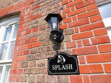 A black wall lantern and a house sign with a horse head and the word Splash on a brick wall at Splash in Weymouth