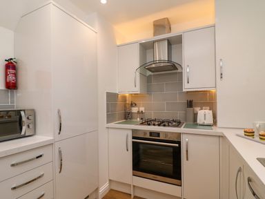 A kitchen with white cabinets a stainless steel oven and stove a microwave a fire extinguisher and a toaster at Splash in Weymouth