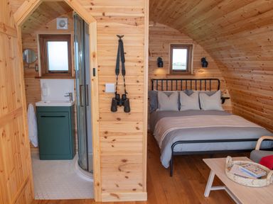 A wooden pod interior with a bed and bathroom at Glamping Pod 2 Presence in Lebberston