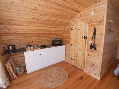 A small kitchenette with a kettle microwave sink and coffee setup inside a wooden cabin at Glamping Pod 2 Presence in Lebberston